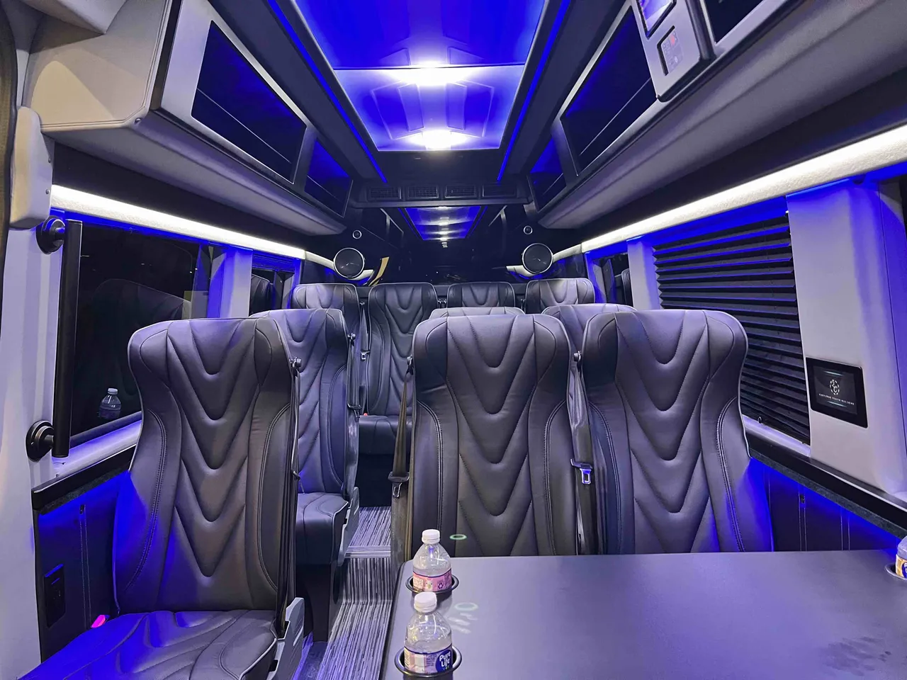 14 Passenger 2024 Mercedes-Benz Executive Sprinter cabin view with captain's chairs, passenger tables and cup holders