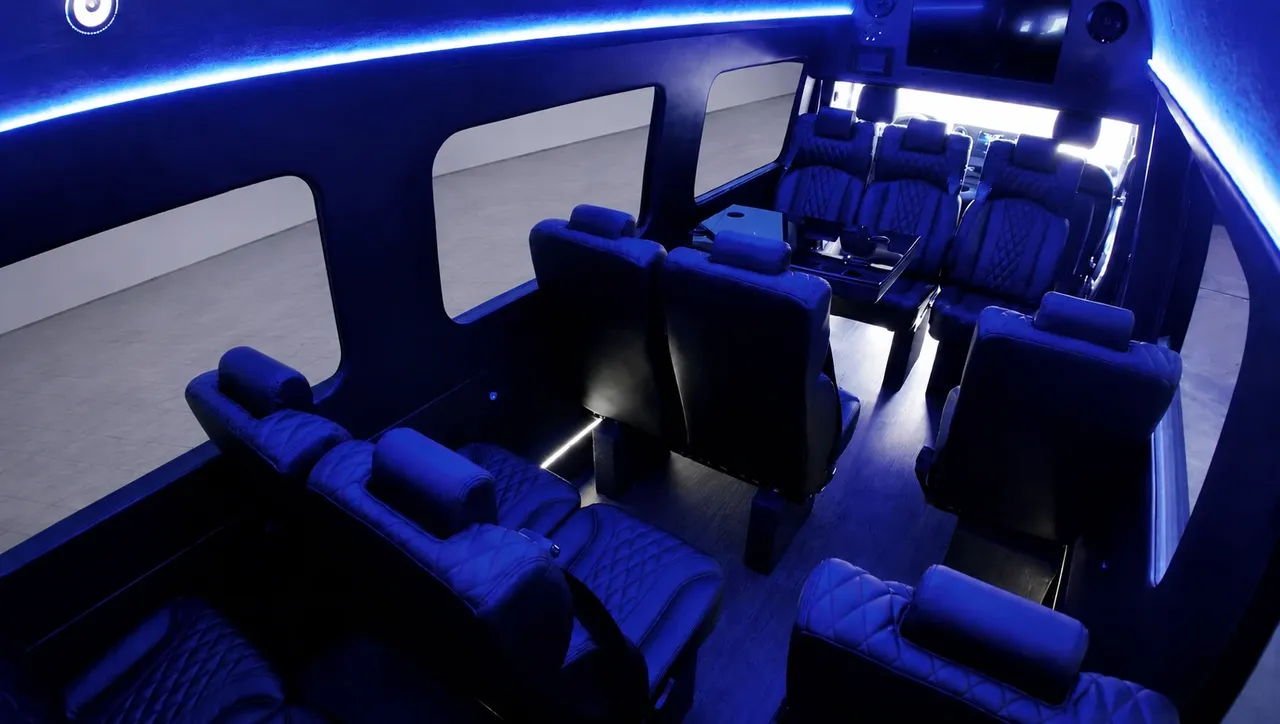 Black Luxury Sprinter Shuttle Van cabin view, angle 3 with captain's chairs, passenger tables and LED accent lighting