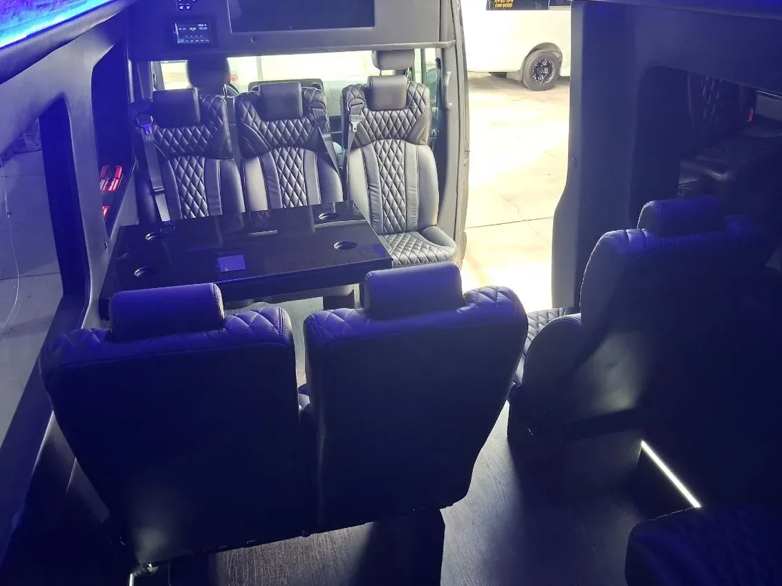 Black Luxury Sprinter Shuttle Van cabin view with captain's chairs, passenger tables and LED accent lighting