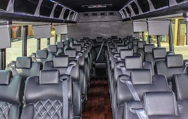 38 Passenger Executive Mini Coach 38 Passenger Executive Mini Coach cabin view with airline-style seats, wood-look flooring and TV screens