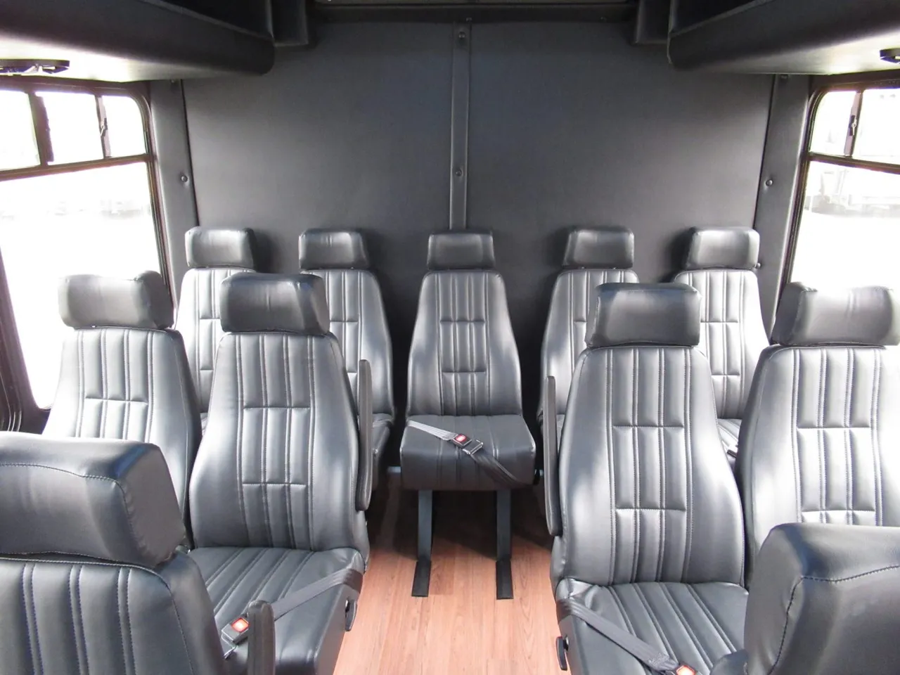28 Passenger Ford F550 Executive VIP Mini Coach cabin view, angle 3 with wood-look flooring and passenger seat belts