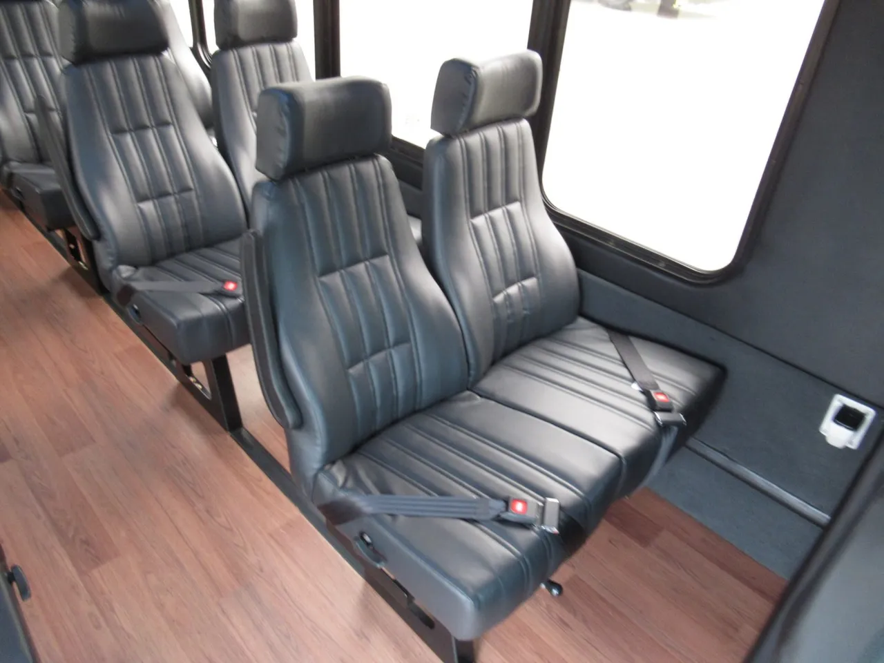 32 Passenger Ford F600 Executive VIP Shuttle Bus cabin view with wood-look flooring and passenger seat belts