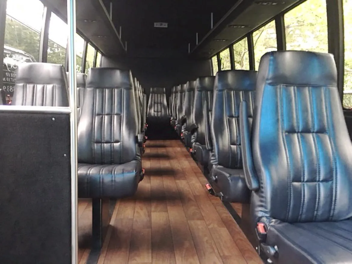 28 Passenger Ford F550 Executive VIP Mini Coach 28 Passenger Ford F550 Executive VIP Mini Coach cabin view with wood-look flooring and passenger seat belts