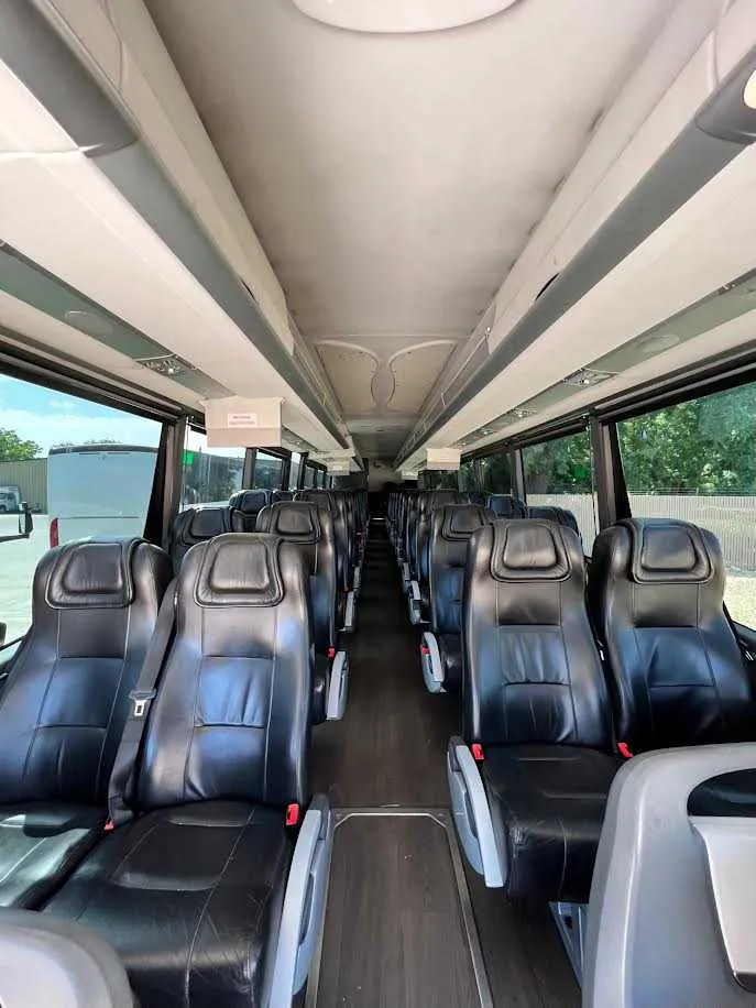 MCI Motorcoach cabin view with passenger seat belts and overhead parcel racks