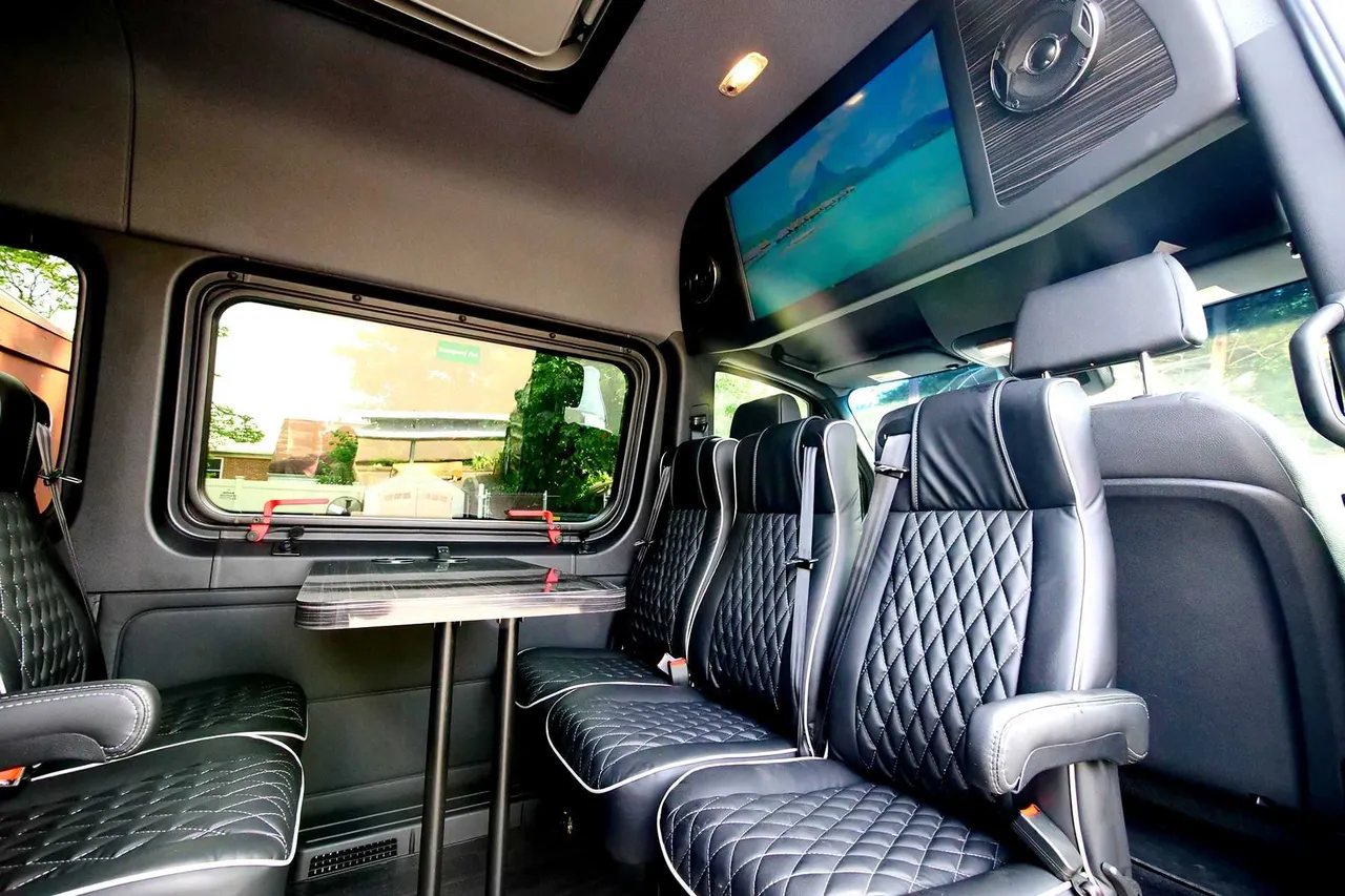 Mercedes-Benz Executive Sprinter cabin view with passenger tables and TV screens