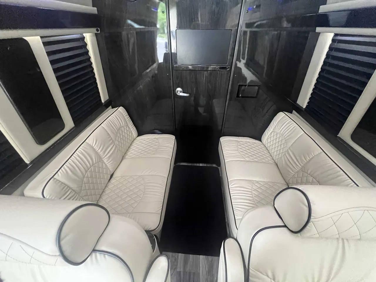 Mercedes-Benz Executive Sprinter cabin view with sofa-style seating, window shades and wood-look flooring