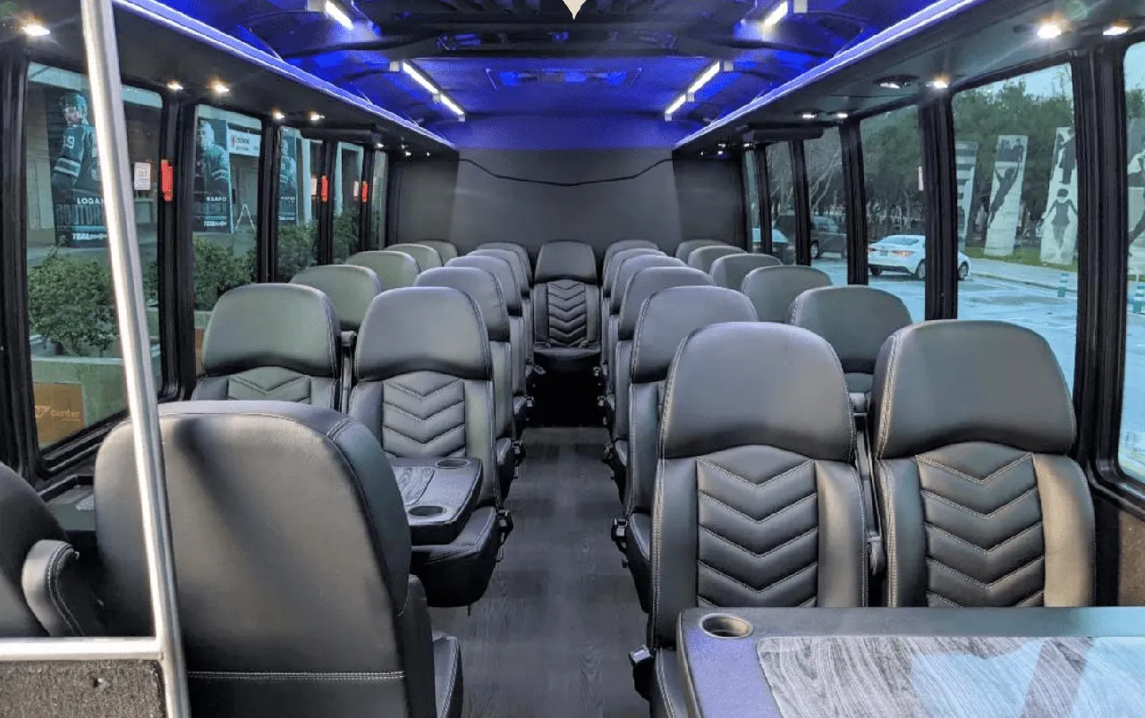 27 Passenger Mini Coach cabin view with passenger tables, cup holders and LED ceiling lighting