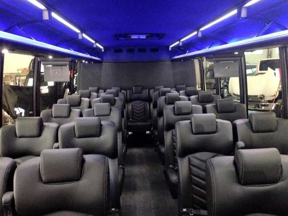 28 Passenger Mini Coach cabin view with airline-style seats, LED ceiling lighting and TV screens