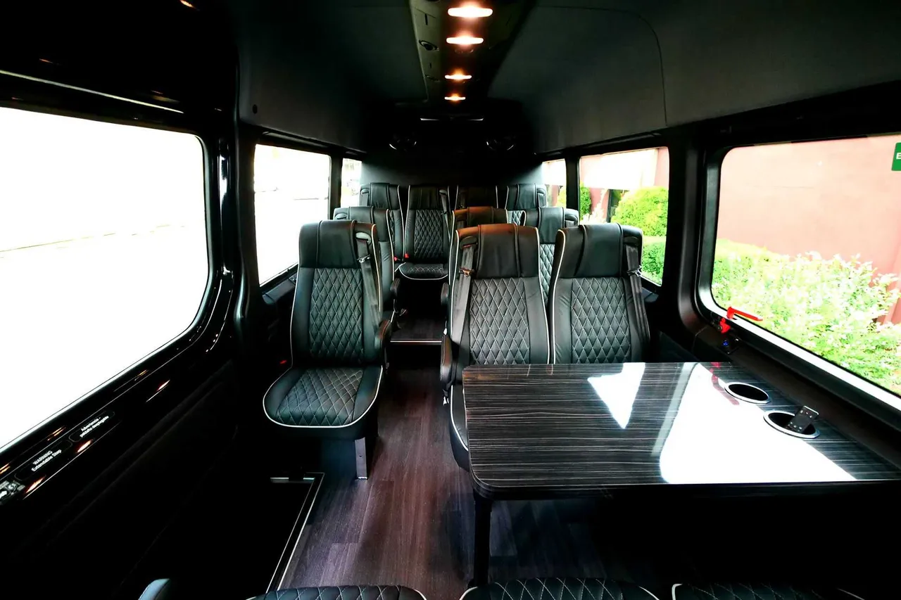 24 Passenger Mini Coach cabin view with captain's chairs, passenger tables and cup holders