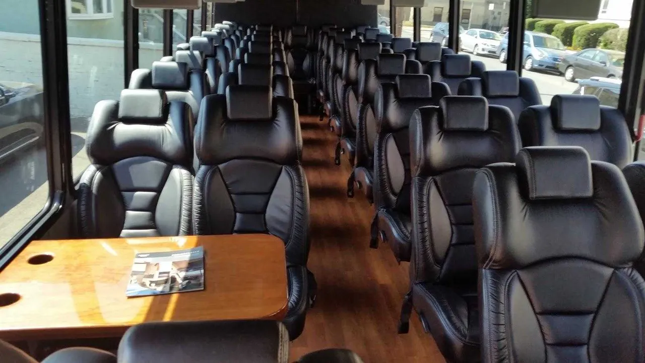 36 Passenger Mini Coach cabin view with passenger tables and wood-look flooring
