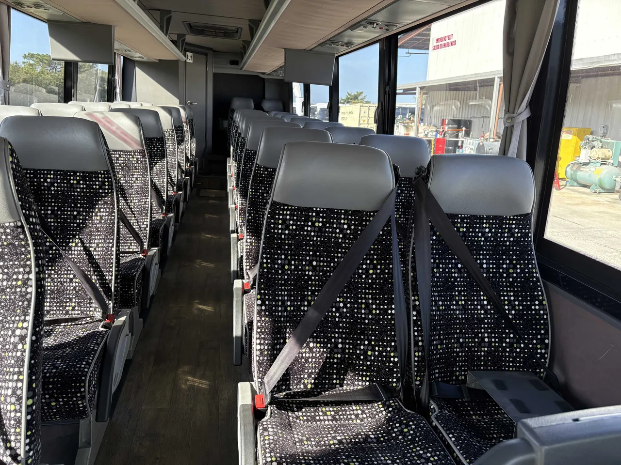 24 Passenger Mini Coach cabin view with window shades, wood-look flooring and passenger seat belts