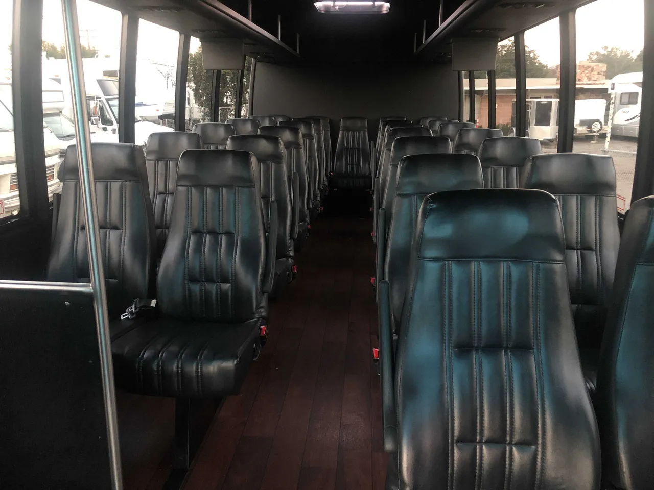 21 Passenger Mini Coach cabin view with airline-style seats, wood-look flooring and grab handles and rails