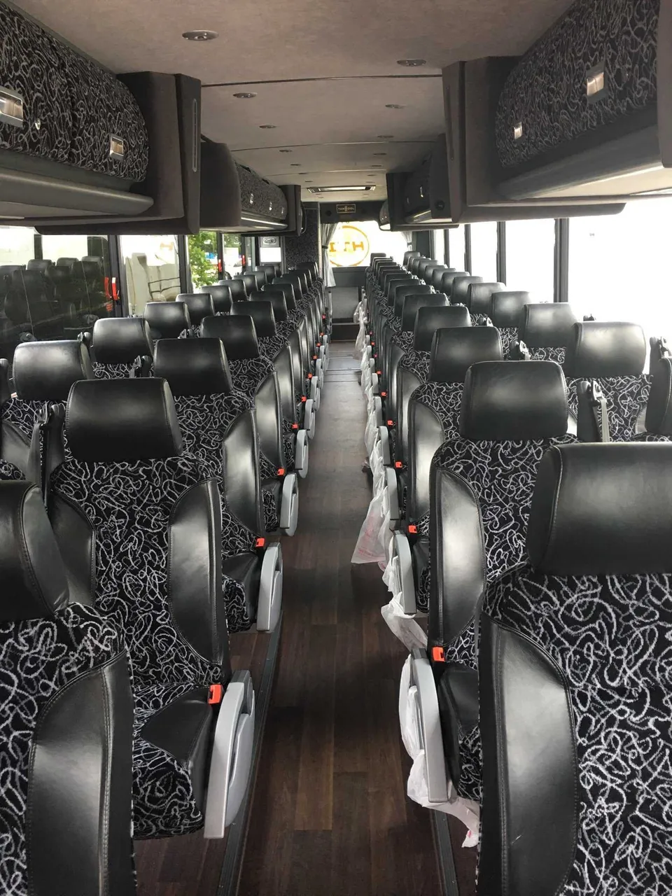 56 Passenger Motor Coach cabin view with passenger seat belts and overhead parcel racks