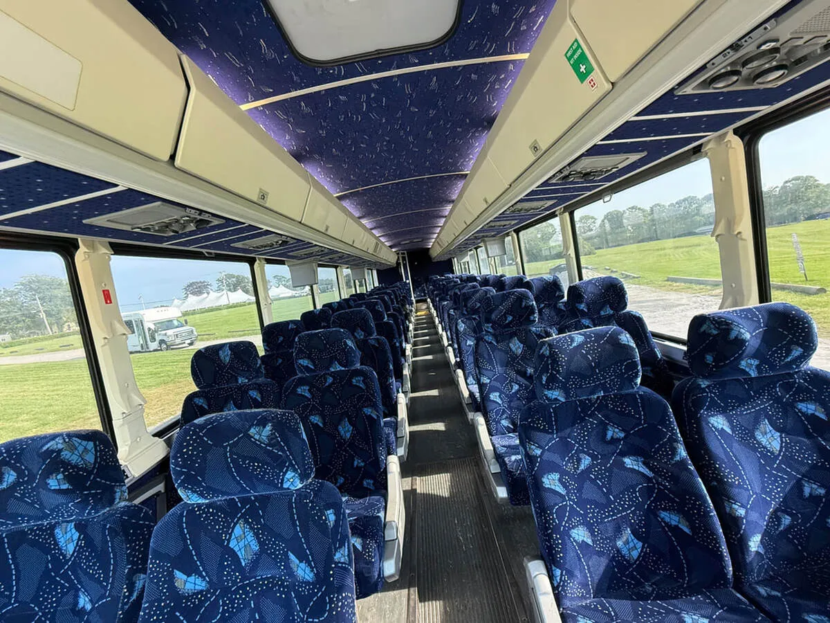 Motor Coach Luxury (Cloth Seats) cabin view with overhead parcel racks