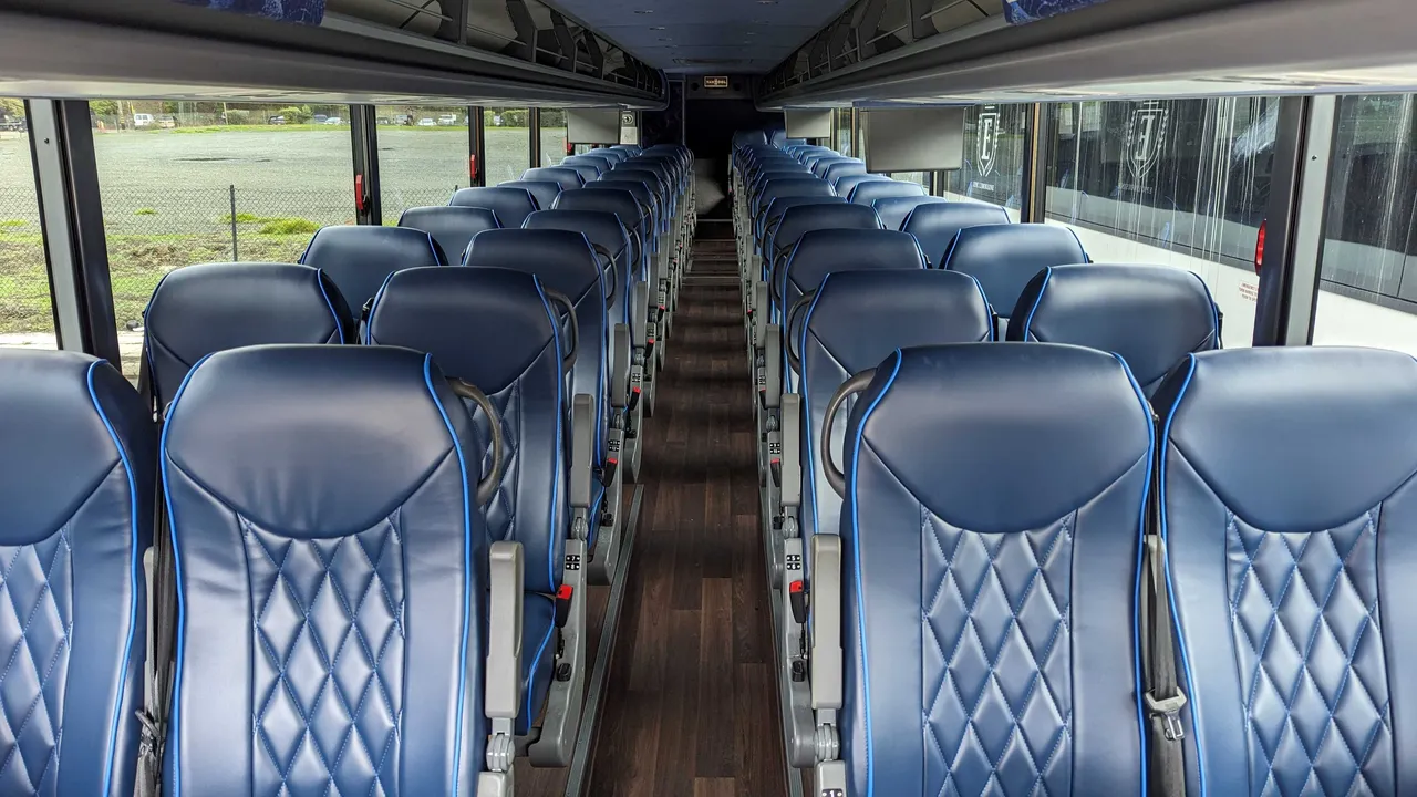 56 Passenger Motorcoach cabin view with passenger seat belts and overhead parcel racks