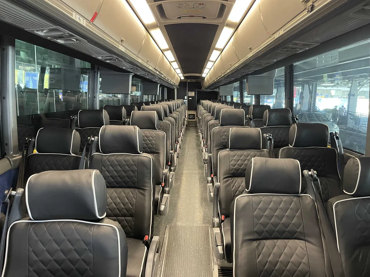 56 Passenger Motorcoach cabin view with TV screens and overhead parcel racks
