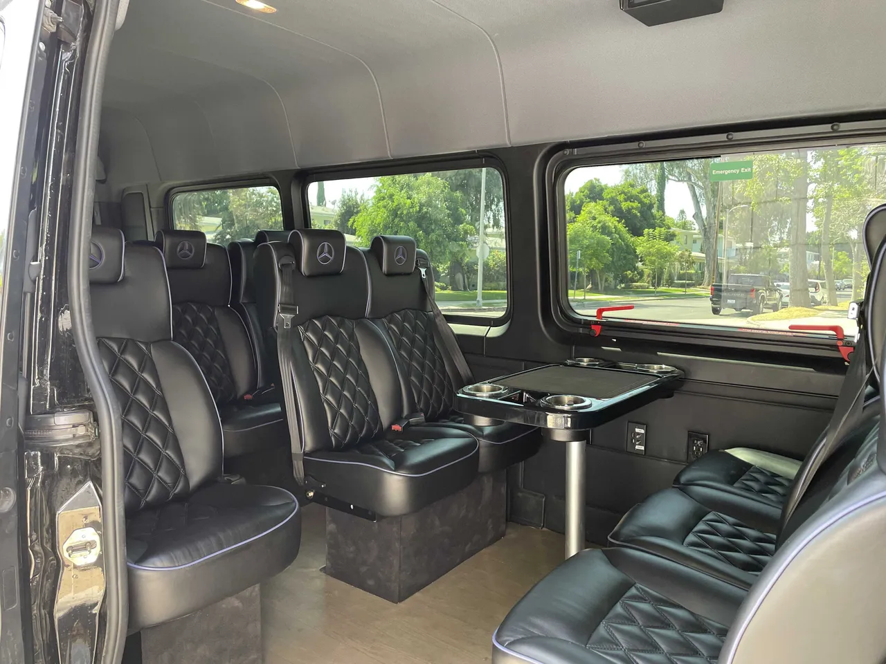 Sprinter Van cabin view with captain's chairs, conference-style seating and passenger tables
