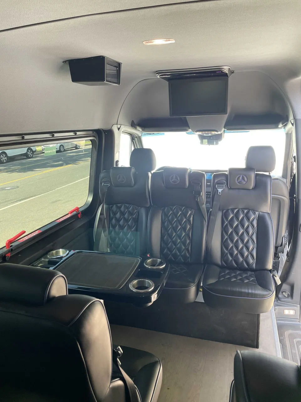 Sprinter Van cabin view with captain's chairs, passenger tables and cup holders