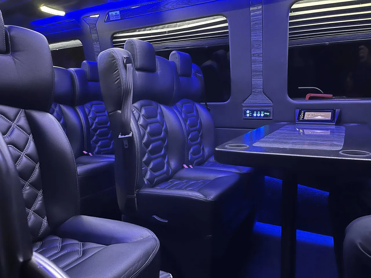 Sprinter VIP Van cabin view with captain's chairs, passenger tables and cup holders