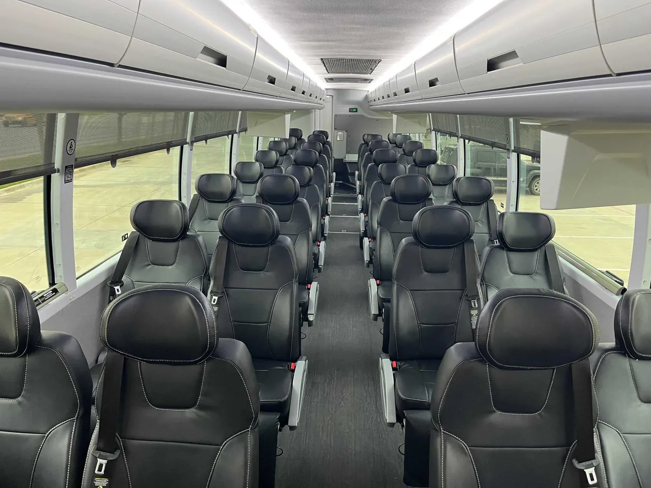 Executive Recliner Motorcoach cabin view with window shades, LED ceiling lighting and overhead parcel racks